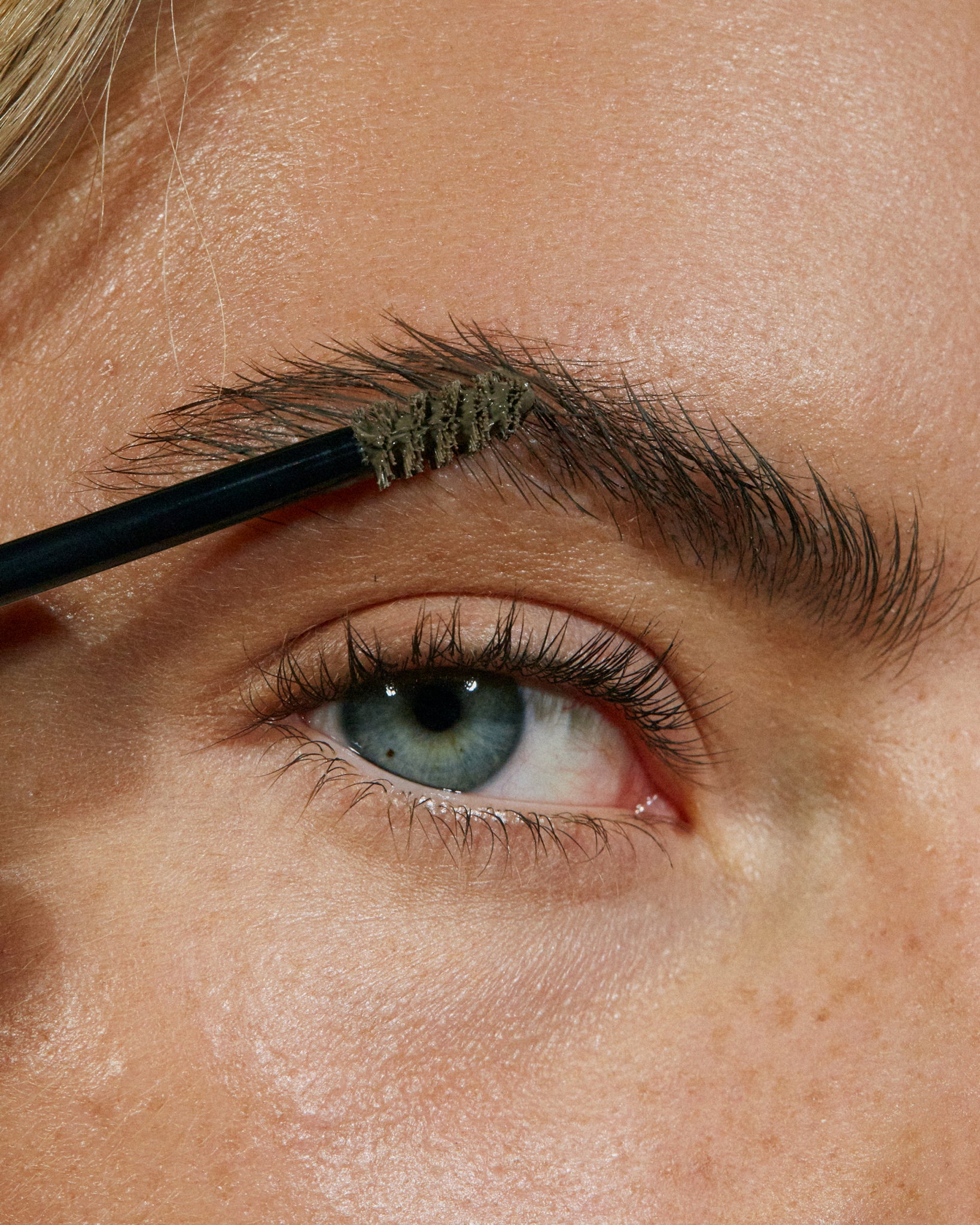 Model wearing MÁDARA Organic Skincare brow and lash booster frosty taupe on A6703 on skin; close-up portrait shows natural application results.