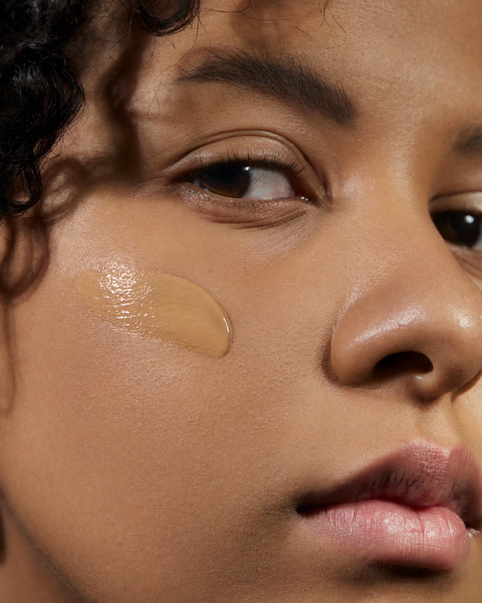 Model wearing MÁDARA Organic Skincare skinonym foundation warm tan on A6092 foundation on skin; close-up portrait shows natural application results.